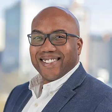 person wearing glasses and suit smiling at camera