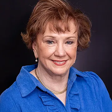 person smiling at camera wearing bright blue ruffled shirt