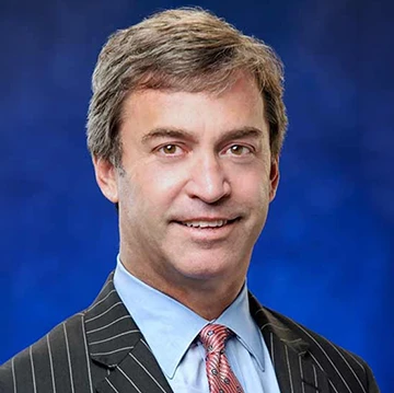 person in suit smiling at camera; bright blue background