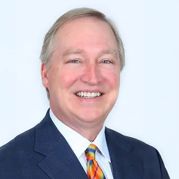 person in suit smiling; white background