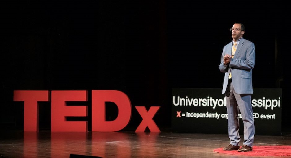 faculty member standing on a stage with the TEDX logo