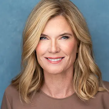 person smiling; blond wavy hair; light blue background