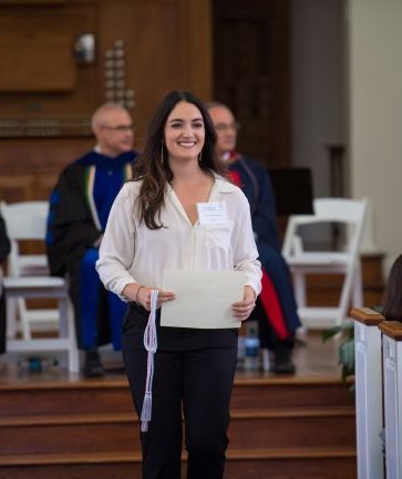 image of student walking in a ceremony holding a certificate.