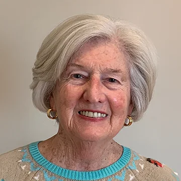 person wearing sweater smiling at camera; gray hair