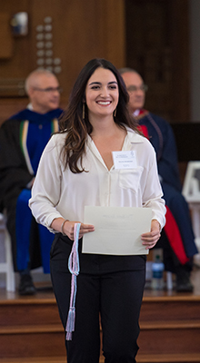 image of student walking in a ceremony holding a certificate.