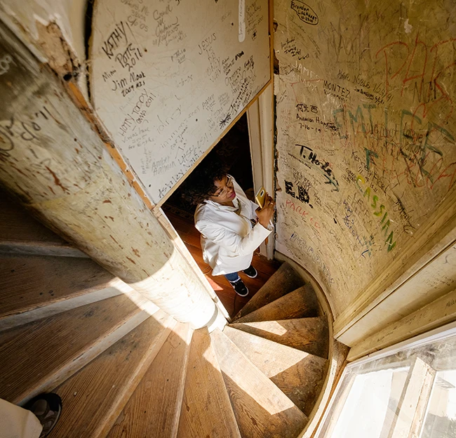 One of the UM Hidden History Tour participants pauses to photograph the graffiti inside the Ventress Hall spire. 