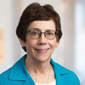 portrait of person smiling, wearing glasses and aqua jacket