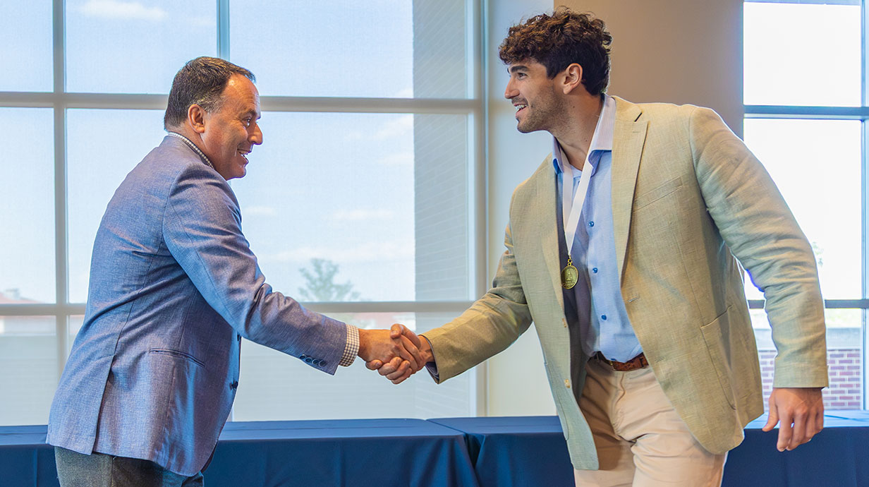 student shaking the hand of the dean while receiving an award