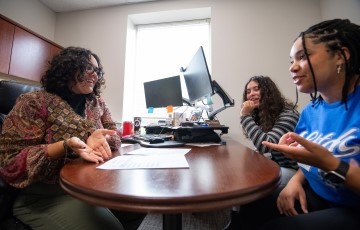 staff member talking with two students in her office