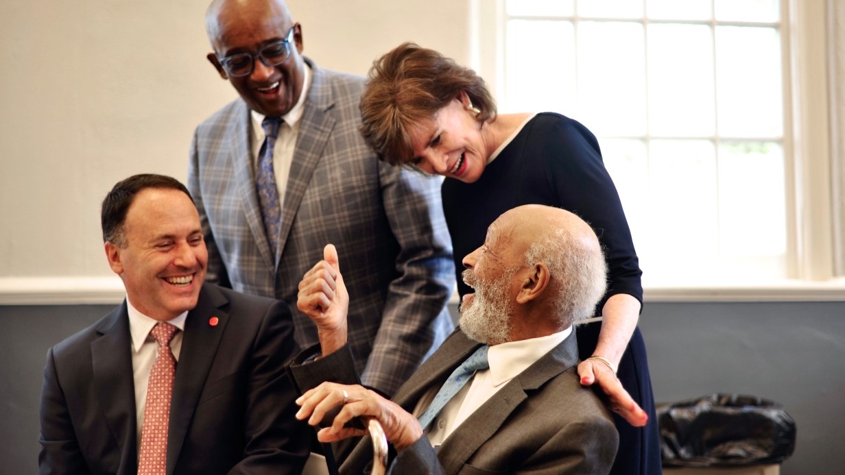 a group of people talking together, with two seated and two standing behind them