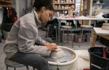 image of a student working on a ceramic bowl at a pottery wheel