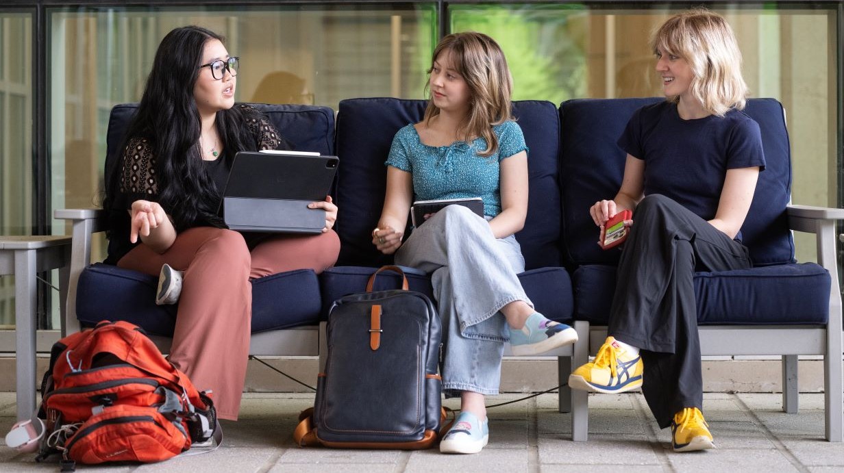 Three female students sitting on a couch in the Union talking