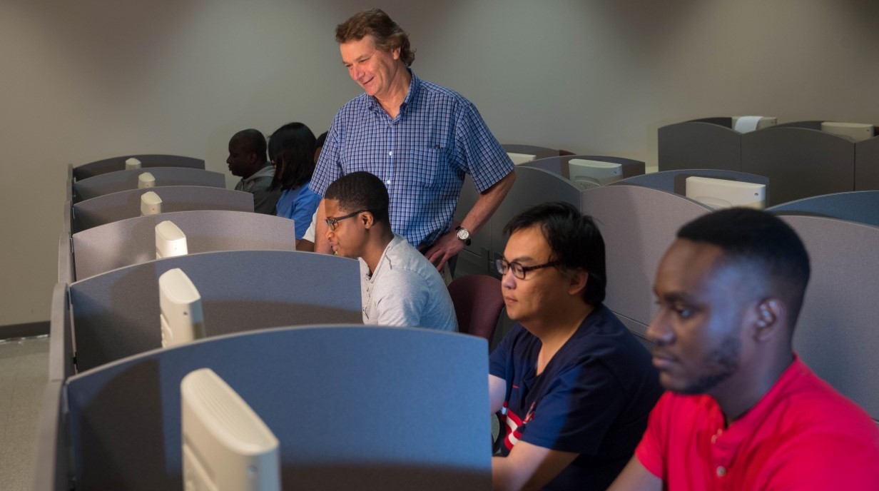 faculty member with students sitting at computers in a lab