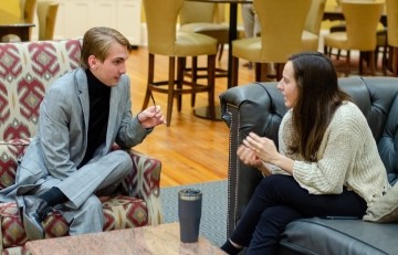 two students sitting in a lobby talking to each other