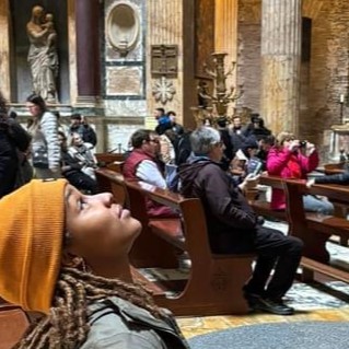 Female student looking up at the ceiling in a historic building in Rome.