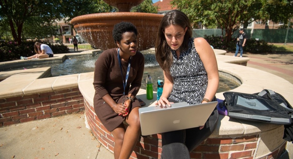 two graduate students sitting together looking at a computer