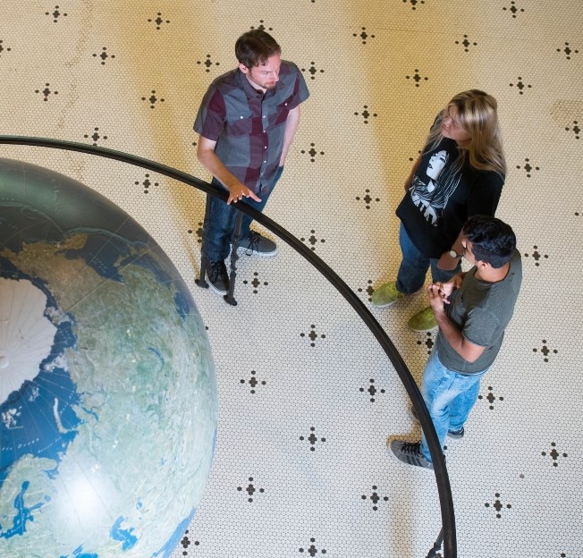 faculty member talking with two students in a lobby