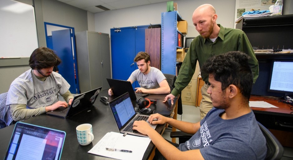 physics graduate students at computers sitting around a table