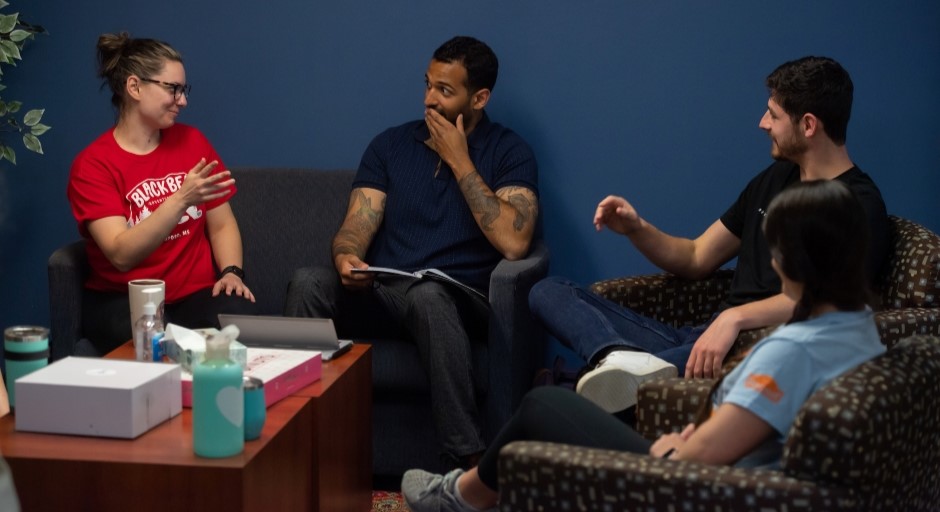 graduate students seated together in casual chairs talking with each other