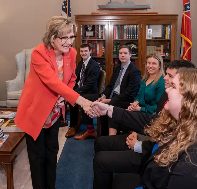 student shaking the hand of a female politician in her office