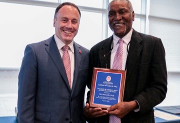 image of Dean giving award to an alum of the College