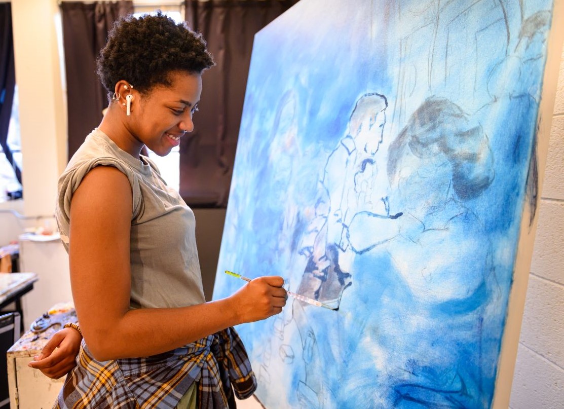 Female student painting a large canvas