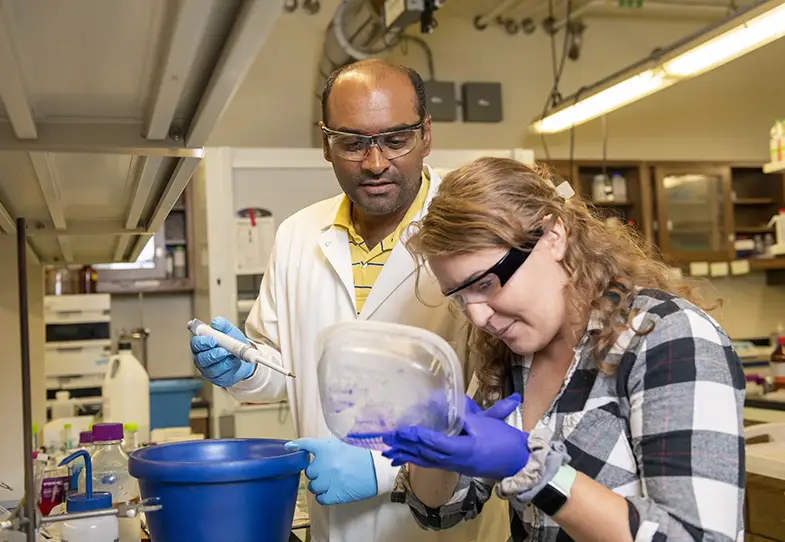 Professor and student working in a lab. Professor holds pipette and student holds specimen.