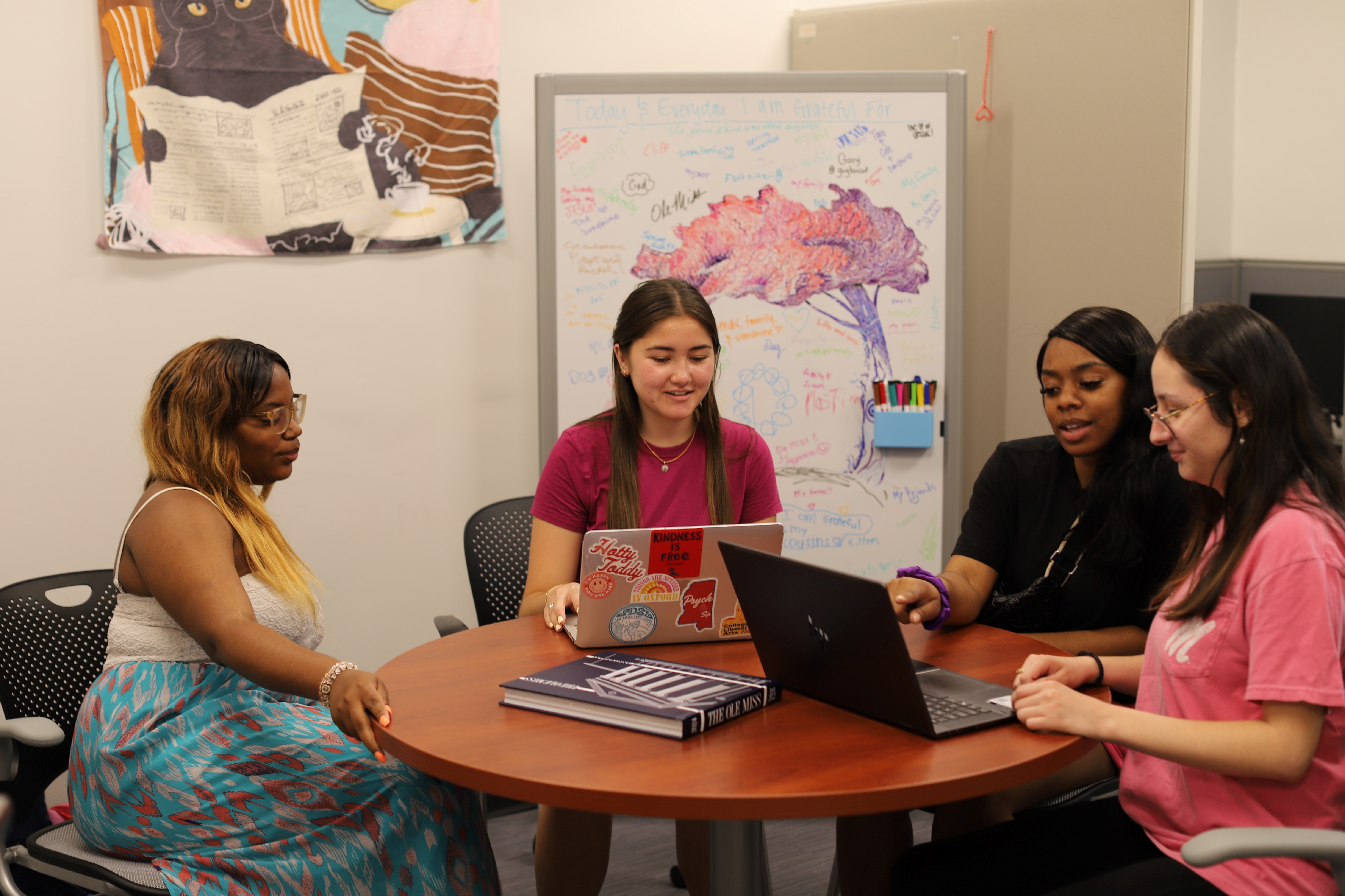 Four psychology students sit around a table and discuss research results.