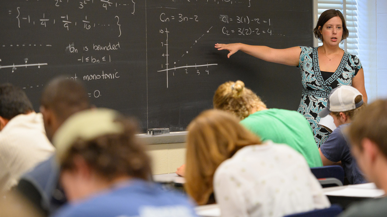 female professor teaching in front of chalkbaord