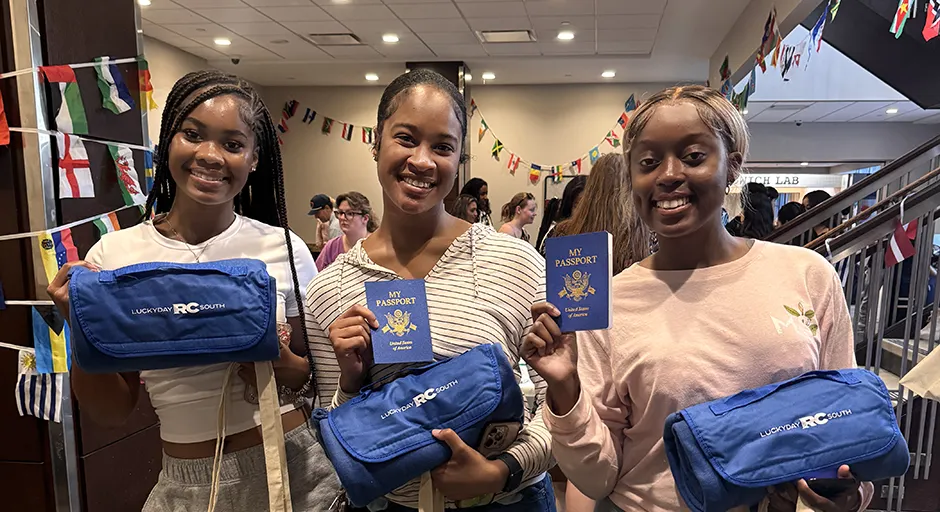 3 smiling students look at the camera and hold passports.