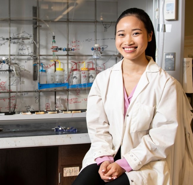 image of a student seated in a chemistry lab with the vent hood behind her