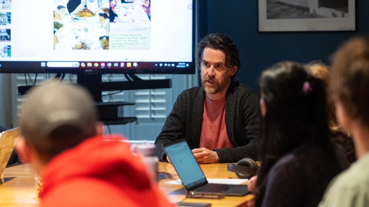 professor seated in a conference table in a graduate course