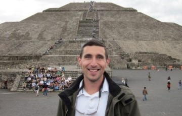 Image of faculty member standing in front of ancient pyramids in Mexico