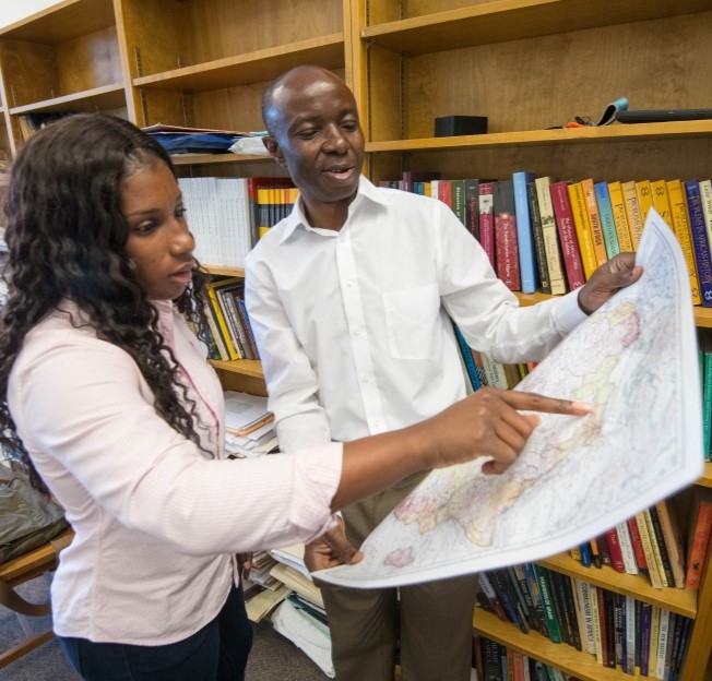 Faculty member and student standing together and looking at a map