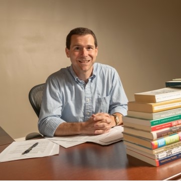  image of faculty member sitting with books in the office