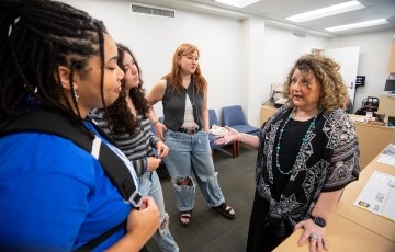 staff member standing in an office talking with a small group of students