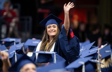 student waving at the camera at graduation ceremony