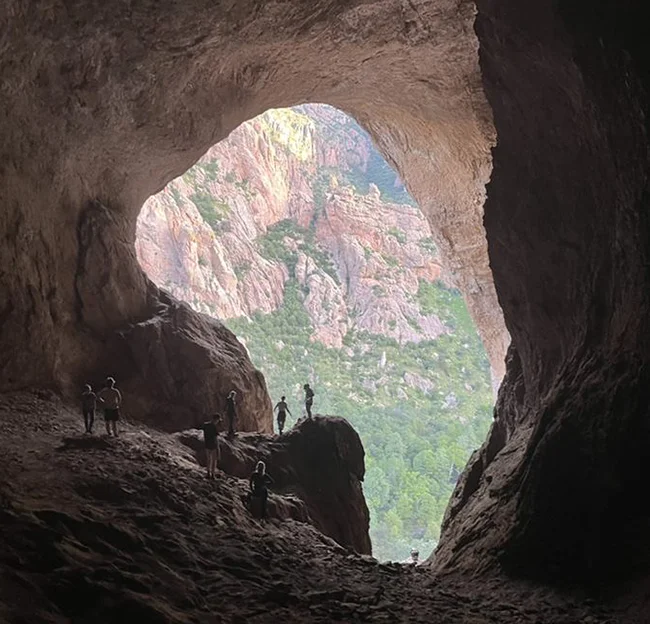 opening of cave. people standing, in silhouette