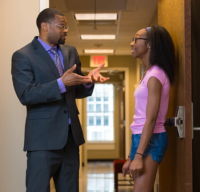 image of faculty member and student standing in the hallway talking