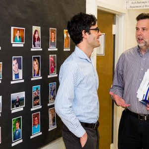 Department of History Chair Joseph P. Ward, right, chats with Zachary Kagan Guthrie, assistant professor of history, near a wall showcasing the department's graduate students. The Brig. Gen. John H. Napier III Endowment will support research efforts of the Arch Dalrymple III Department of History faculty and doctoral students.