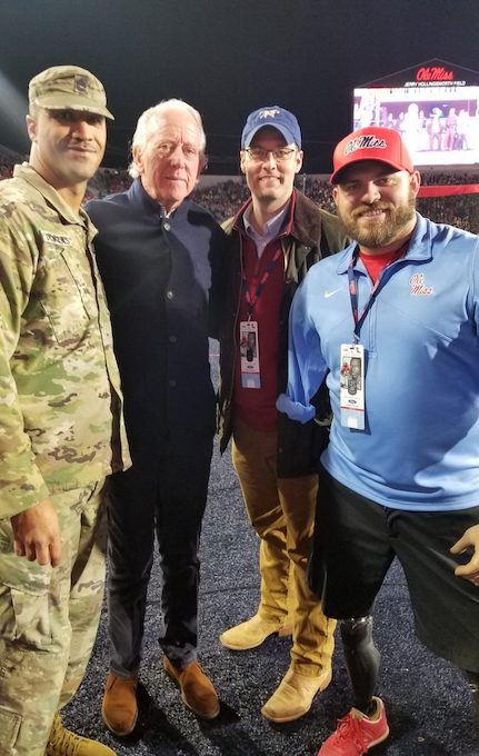 Bestselling author and combat-wounded quadruple amputee Travis Mills (right) gets the VIP treatment at a UM football game, including meeting Ole Miss football great Archie Manning (second from left). 
