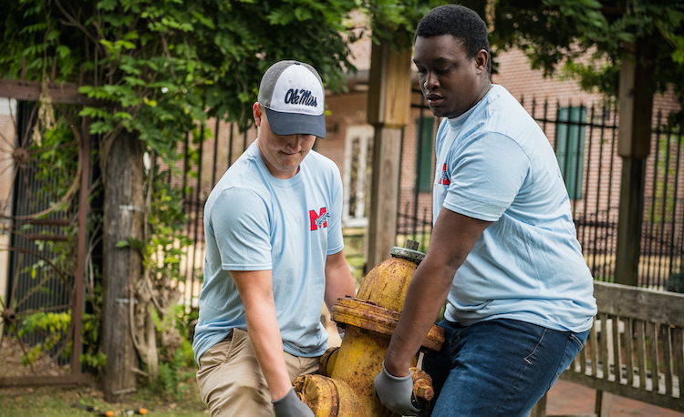 Archive Photo: UM students work to move a fire hydrant during an M Partner Community Day event in 2018. M Partner was launched as a community engagement effort seeking to improve life in Mississippi communities, specifically in Charleston, Lexington and New Albany for the pilot phase. Photo by Megan Wolfe/Ole Miss Digital Imaging Services