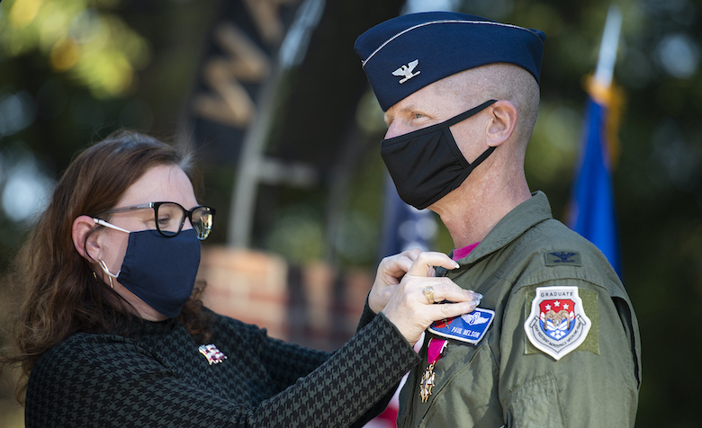 Betsy Nelson pins an Air Force retirement pin to her husband’s flight suit. Col. Paul ‘Voodoo’ Nelson held his retirement ceremony at the Walk of Champions, the same place he was commissioned more than three decades earlier. Photo by Logan Kirkland/Ole Miss Digital Imaging Services