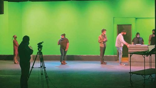 Cast members for the production of ‘Urinetown’ rehearse before a green screen in Meek Hall Auditorium....
