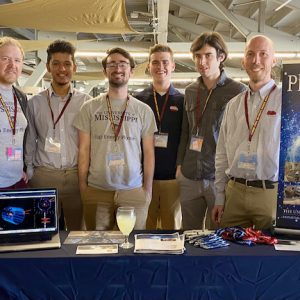 The University of Mississippi table at the 88th conference of the American Physical Society Southeastern Section at Florida State University in Tallahassee in November 2021 are pictured from left to right: Gavin Davies, assistant professor working on experimental particle physics with the NOvA experiment; Sakul Mahat; Paul Gebeline; Wil Stacy; Matthew Mestayer; and Jake Bennett, assistant professor working on experimental particle physics with the Belle II experiment.
