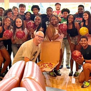 Grove Scholars director Gray Flora IV (center with pizza) took the 2022 freshman cohort bowling to help them bond and de-stress prior to beginning their collegiate experience.