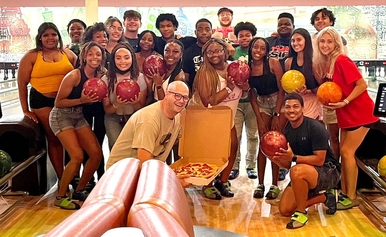 Grove Scholars director Gray Flora IV (center with pizza) took the 2022 freshman cohort bowling to help them bond and de-stress prior to beginning their collegiate experience.