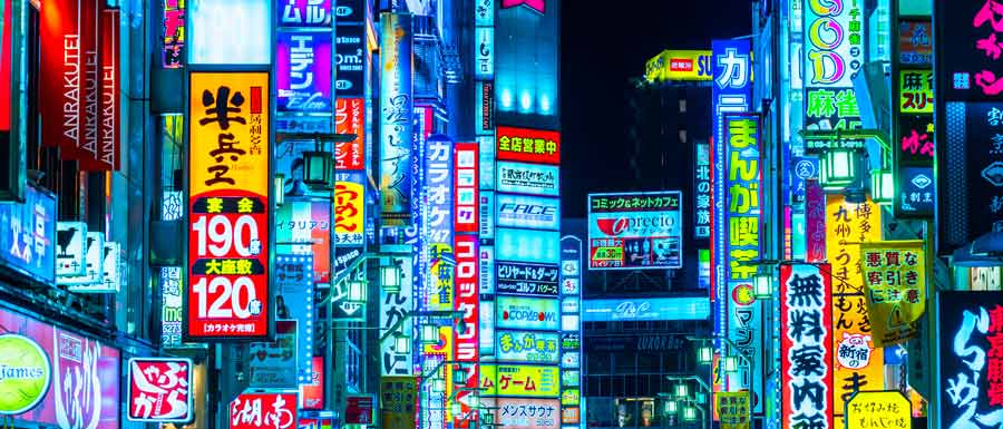 City scene of Japan at night. Image features many colorful illuminated neon signs.