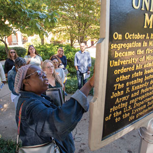 Rhondalyn Peairs looking up at a historical marker while group of 6 adults in background watch.